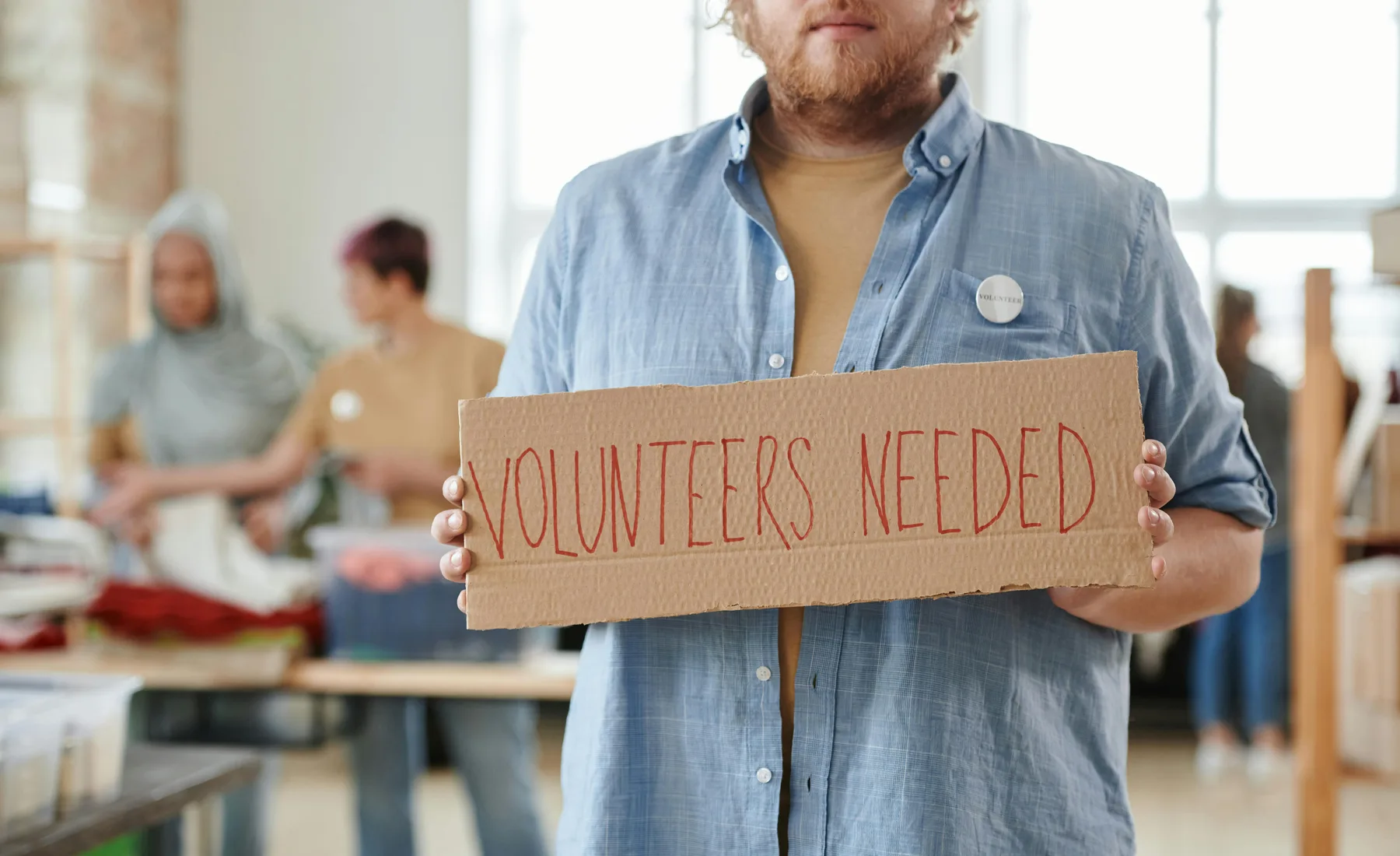 A volunteer holding a handmade sign at a community aid event.
